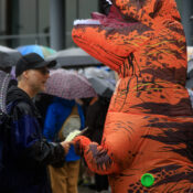 a man talking to a big inflated tyrannosaur - with a person hidden inside.