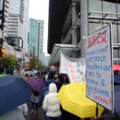 from behind, marchers near Jack Poole Plaza, with a sign reading "Bill C-2" (which is crossed out) and "Government overreach threatens our rights to privacy and due process in Canada