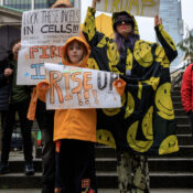 A family of three holding signs: Dump Trump; Rise Up; Lock these Incels in cells!